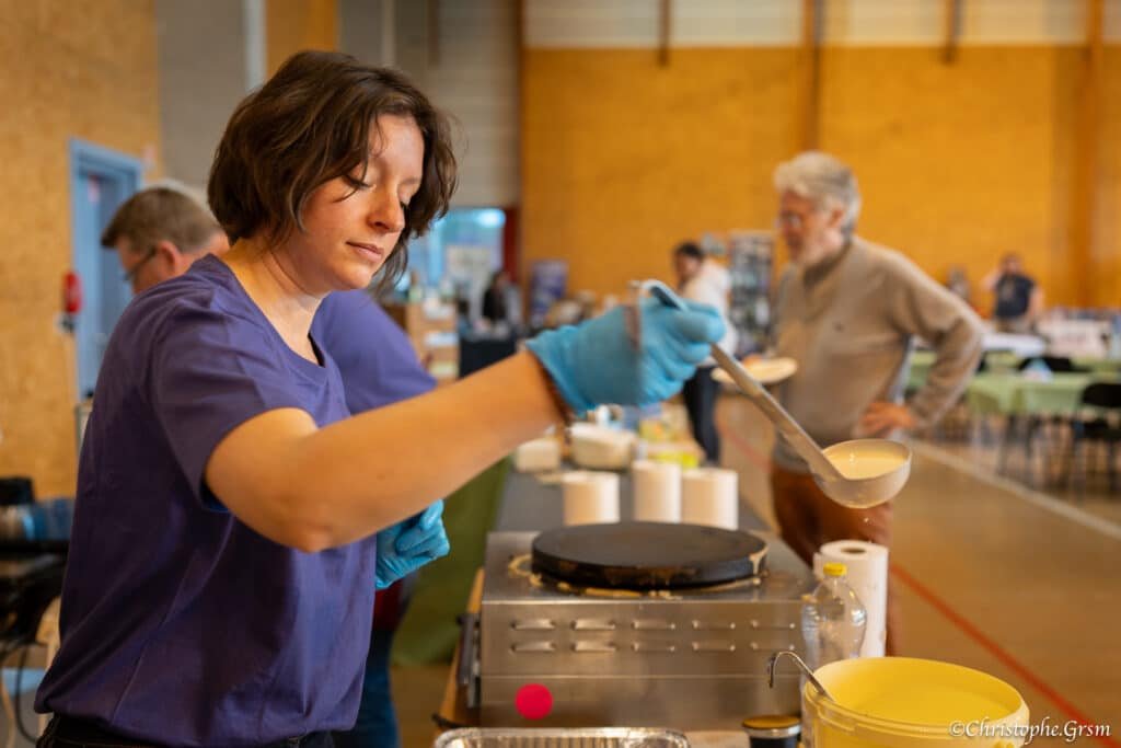 Stand crêpes avec une bénévole en train d'en préparer durant le festival de jeux Ludi'Vaux 2025 Stand crêpes avec une bénévole en train d'en préparer durant le festival de jeux Ludi'Vaux 2025