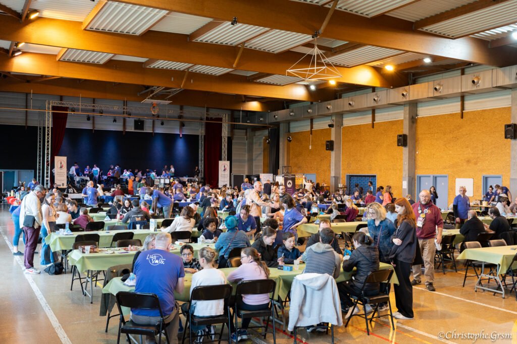 Vue d’ensemble de la salle principale de Ludi’Vaux 2025, pleine de festivaliers Vue d’ensemble de la salle principale de Ludi’Vaux 2025, pleine de festivaliers